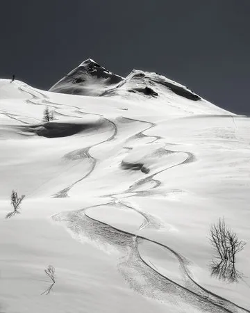 Zwart-wit verticale foto van skiërs in een bevroren alpse landschap met sneeuwsporen en bergen op de achtergrond