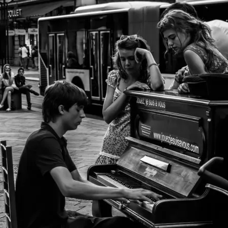 Zwart-wit vierkante foto van een pianist die buiten speelt voor een aandachtig publiek