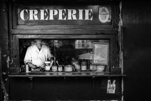 Zwart-witfoto van creperie en mensen op straat in Montmartre, Parijs, met vintage en retro sfeer