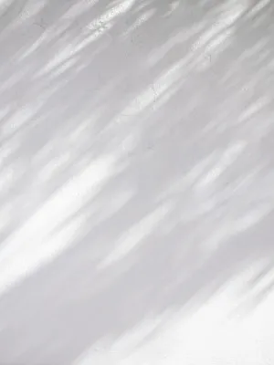 Verticale minimalistische foto van witte en beige stucco muur met licht en schaduwspel in buitenlucht, winterse sfeer