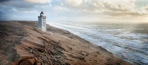 Panoramafoto van Rubjerg Knude vuurtoren en kustlijn in Denemarken met verweerde gebouwen en maritiem landschap