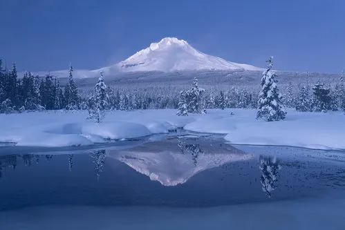 Winters landschap bij Mount Hood met bevroren bergmeer en besneeuwde bomen in blauwe tinten
