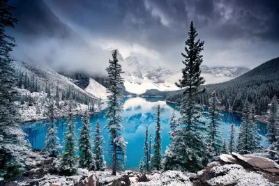 Horizontale foto van het turquoise water van Moraine Lake met besneeuwde dennenbomen in de Canadese Rocky Mountains