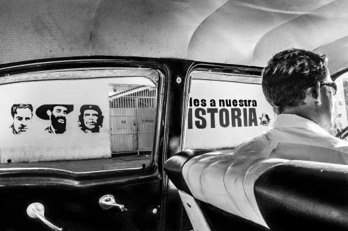 Zwart-wit horizontale foto van straat in Havana met klassieke auto's en man met bril