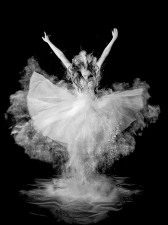 Verticaal zwart-wit portret van een ballerina die springt met een poederexplosie rond haar in een minimalistische setting