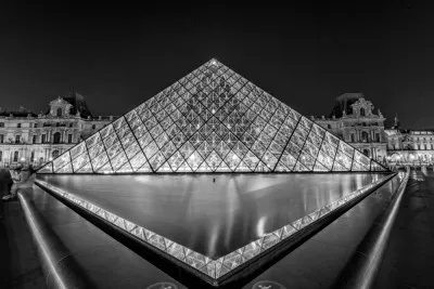 Zwart-wit foto van nachtelijke Parijse skyline met glazen piramide en reflecties in water