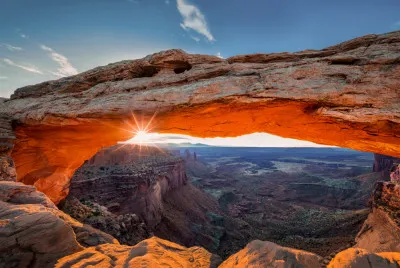 Horizontale landschapsfotografie van Mesa Arch bij zonsopgang in Canyonlands National Park, met rotsbogen en gouden ochtendlicht