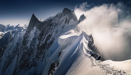 Horizontale foto van een wandelaar op een besneeuwde bergkam met panoramisch uitzicht op Mont Blanc en de Franse Alpen