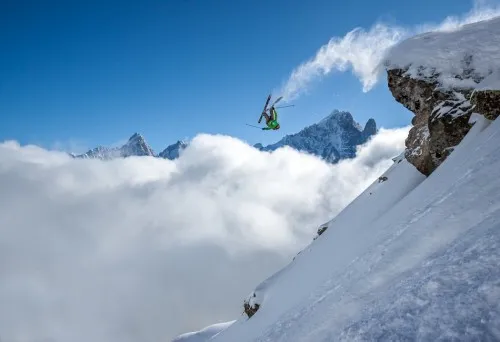 Foto van een skiër die een backflip maakt vanaf een rots in de besneeuwde Alpen bij Chamonix