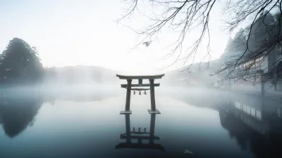 Horizontale panoramafoto van een Japans landschap met mist, water en een torii-poort in de verte