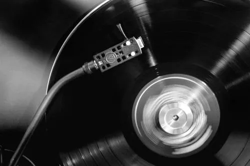 Zwart-witte horizontale fotografie van een vinylplaat en draaitafel in een outdoor setting
