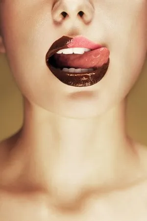 Portret van vrouw met rode lippen en chocolade op haar mond in een intieme keukenomgeving