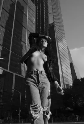 Zwart-wit verticale fotografie van een vrouw in een natuurlijke buitenomgeving, rustgevend en elegant