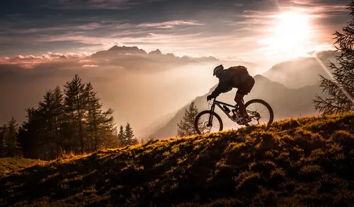 Mountainbiker rijdt tijdens zonsondergang in bergachtig landschap met mist en warm licht