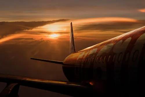 Horizontale foto van een vliegtuig in vlucht tegen een rode zonsondergang met wolken en lucht