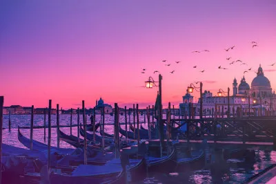 Horizontale foto van een Venetiaans kanaal bij zonsondergang met een gondel en paarse lucht