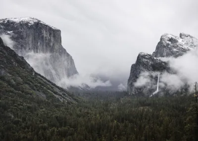 Horizontale foto van Yosemite Valley met El Capitan rots, groene bossen en waterval onder bewolkte lucht