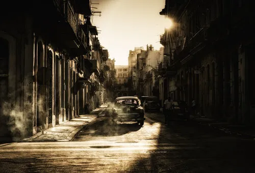 Sepia foto van een straat in Havana met klassieke auto’s, oude gebouwen en ochtendlicht