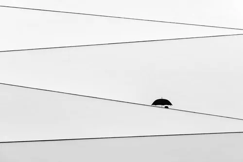 Zwart-wit foto van mensen met paraplu's op een zigzagvormige trap in een minimalistisch landschap