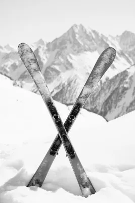 Zwart-wit foto van een skiër op een besneeuwde berghelling in de Alpen onder een bewolkte winterlucht