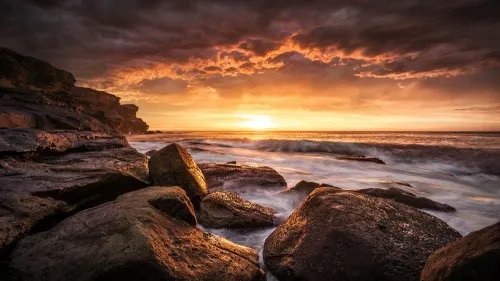Horizontale fotografie van cape solander bij zonsopgang met golven, rotsen en gouden ochtendlicht aan de kust