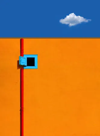 Verticale foto van een oranje afvoerbuis tegen een minimalistische achtergrond van gebouwen en bewolkte lucht in Jaffa