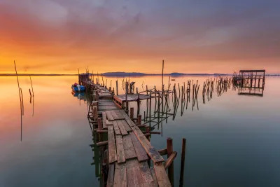 Horizontale foto van een rustige oude houten pier bij zonsondergang in Carrasqueira, Portugal