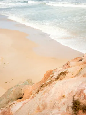 Verticale foto van een rustige zandstrand met golven en rotsachtige kliffen aan de Atlantische kust bij Peniche