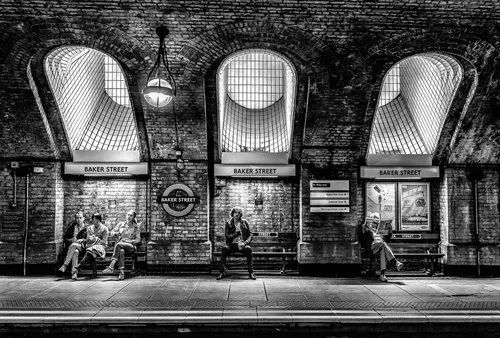 Zwart-wit foto van baker street metrostation met gebouwen en wachtende passagiers in Londen