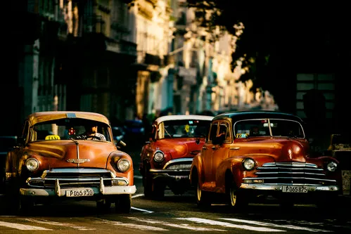 Horizontale foto van Havana straat met klassieke auto's, taxi’s en oude gebouwen in warm ochtendlicht