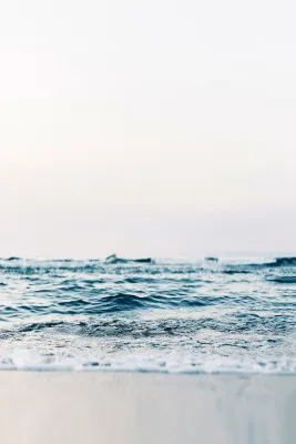 Verticale foto van abstracte golven die zacht over de kustlijn rollen bij een rustige zee