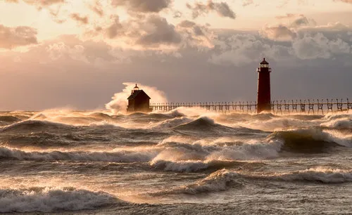 Horizontale foto van raging lake met vuurtoren, pier en golven aan de kust van Lake Michigan