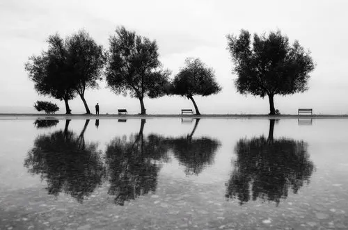 Zwart-wit landschapsfotografie van mensen bij een rivier met bomen en banken, horizontaal beeld
