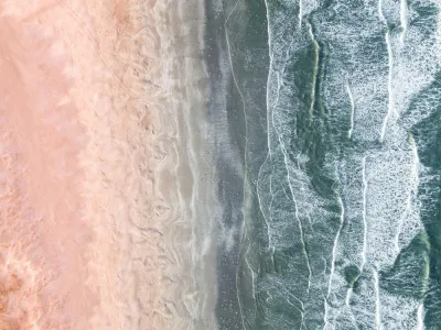 Horizontale luchtfoto van roze en blauwe kustlijn met golven, vogels en seashore in zomerse setting