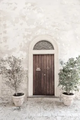 Verticale foto van een oude Italiaanse deur met houten deurknop en bloeiende planten in potten op straat in Noto, Sicilië