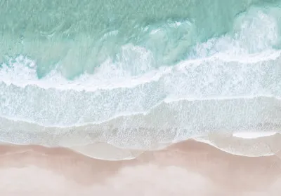 Horizontale luchtfoto van golvende oceaan en kustlijn met zandstrand en blauwe zee