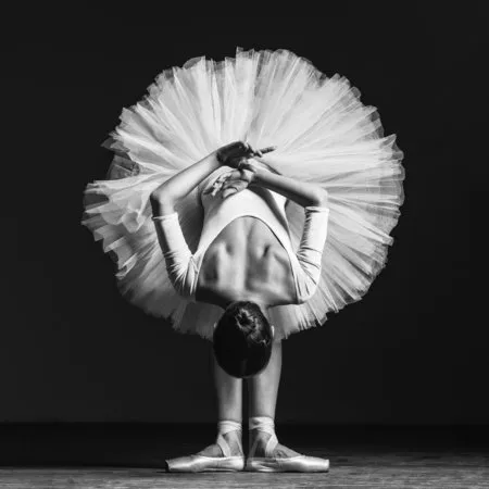 Zwart-wit foto van een ballerina in tutu en balletschoenen in een buitenles